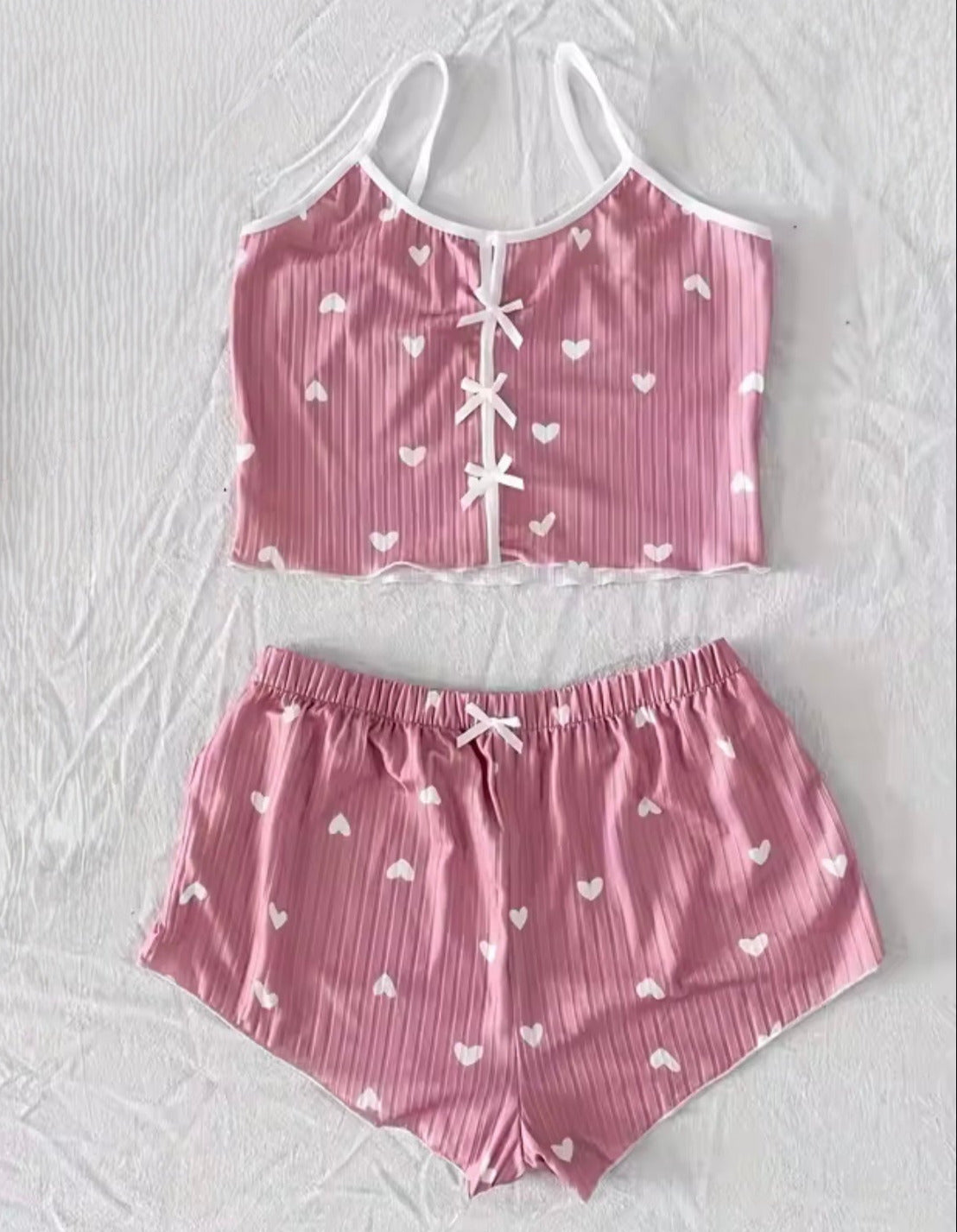 Rosa Pyjama Set mit weißen Herzen und Schleifen, zweiteiliges Set mit Top und Shorts, weicher gerippter Stoff, romantisch und bequem.