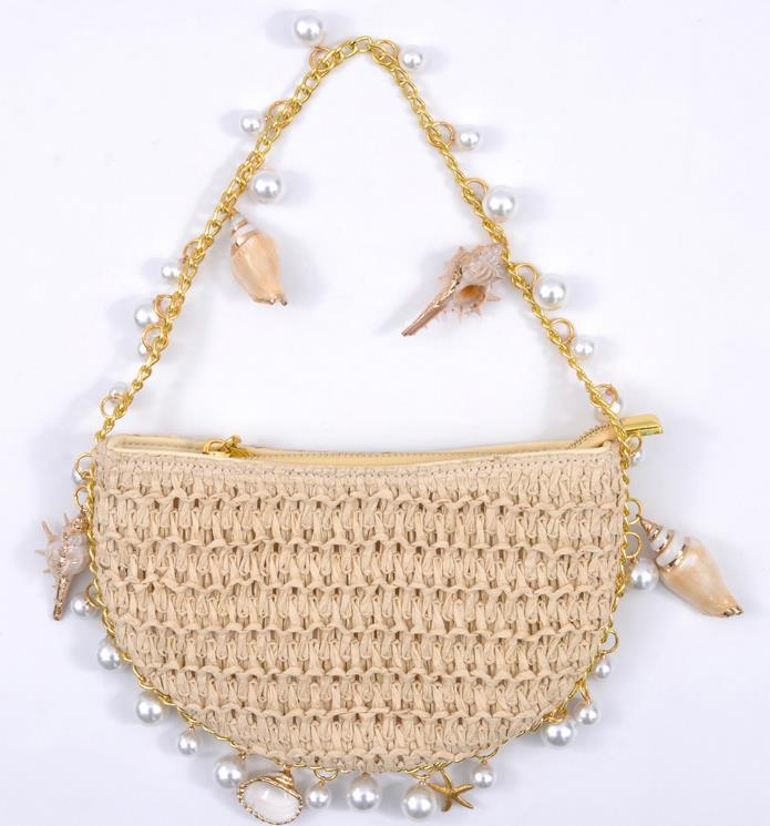 Die flach liegende Ellyysa Muschel Strohhandtasche zeigt das feine Strohgeflecht, goldene Anhänger und Perlen – luxuriöses Sommer-It-Piece.