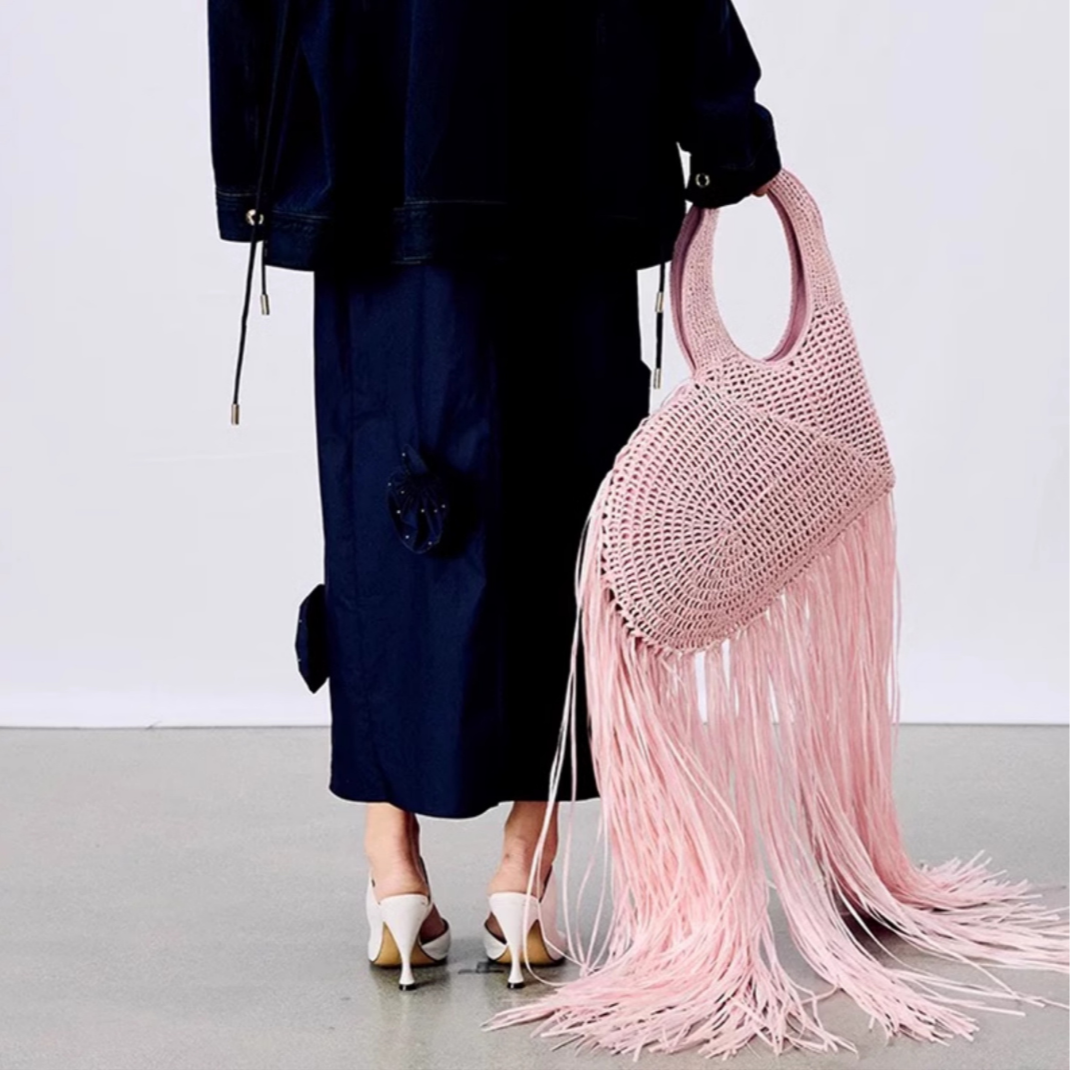 Die Rosyy XXL Herz Fransen Tasche in Rosa zeigt sich seitlich mit langen Fransen – modernes Boho Accessoire mit künstlerischer Handwerkskunst.