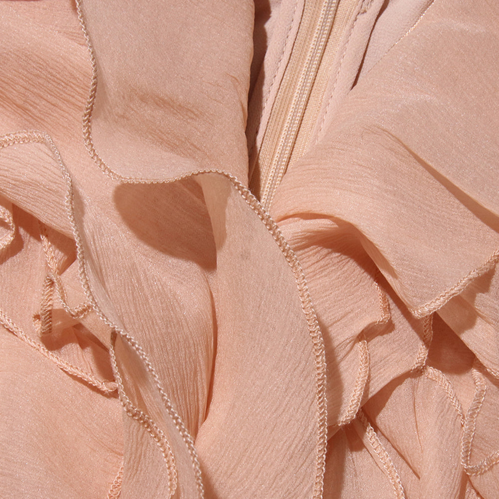 Detailansicht der romantischen Rüschen und Volants des Tarryy Off-Shoulder Kleids – luxuriöser Chiffonstoff in zartem Korallton.