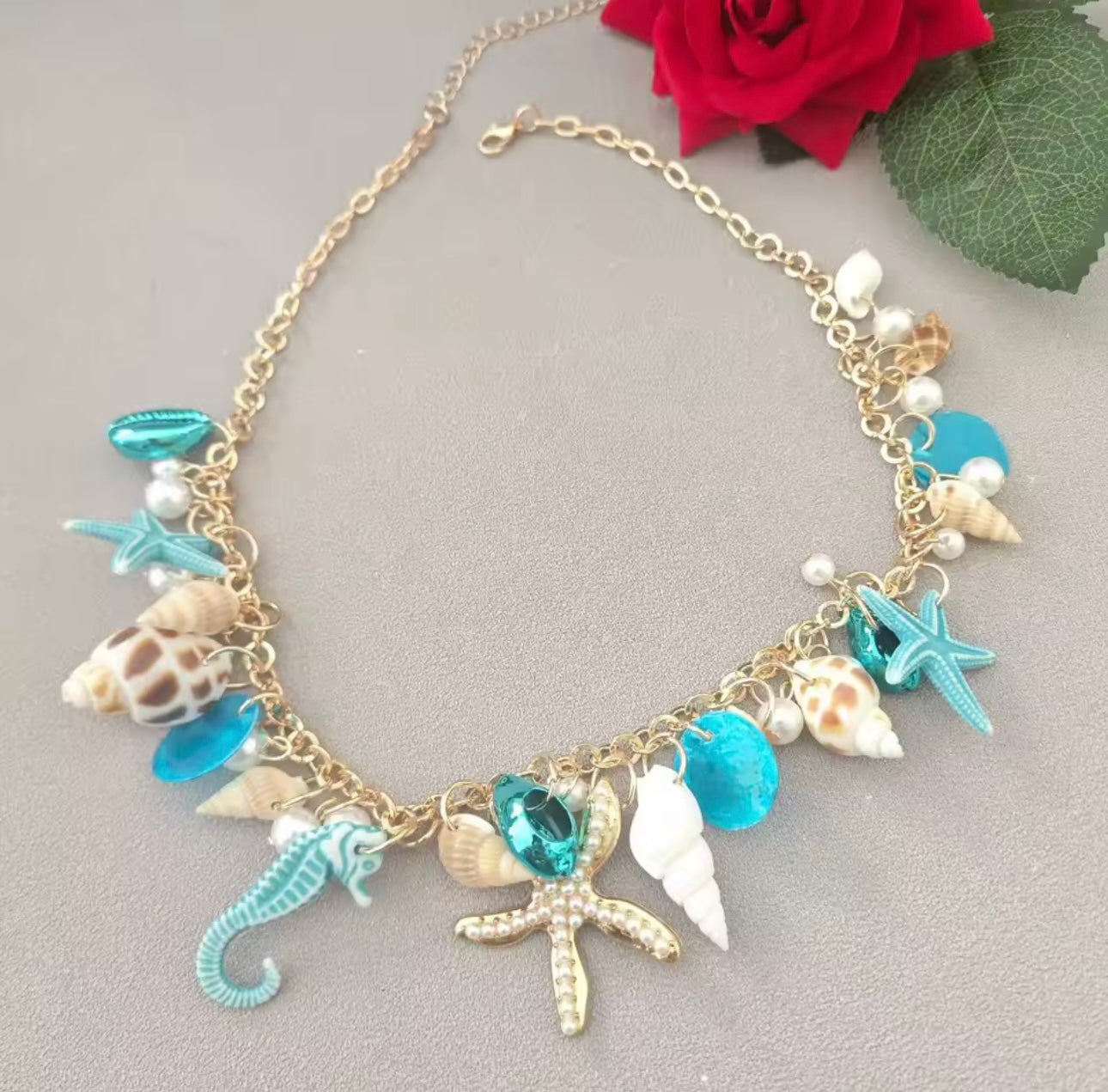 Tyfyy Seestern Muschel Halskette in Blau und Gold, dekoriert mit roter Rose – maritime Statement-Kette mit Seestern, Muscheln und Perlen.