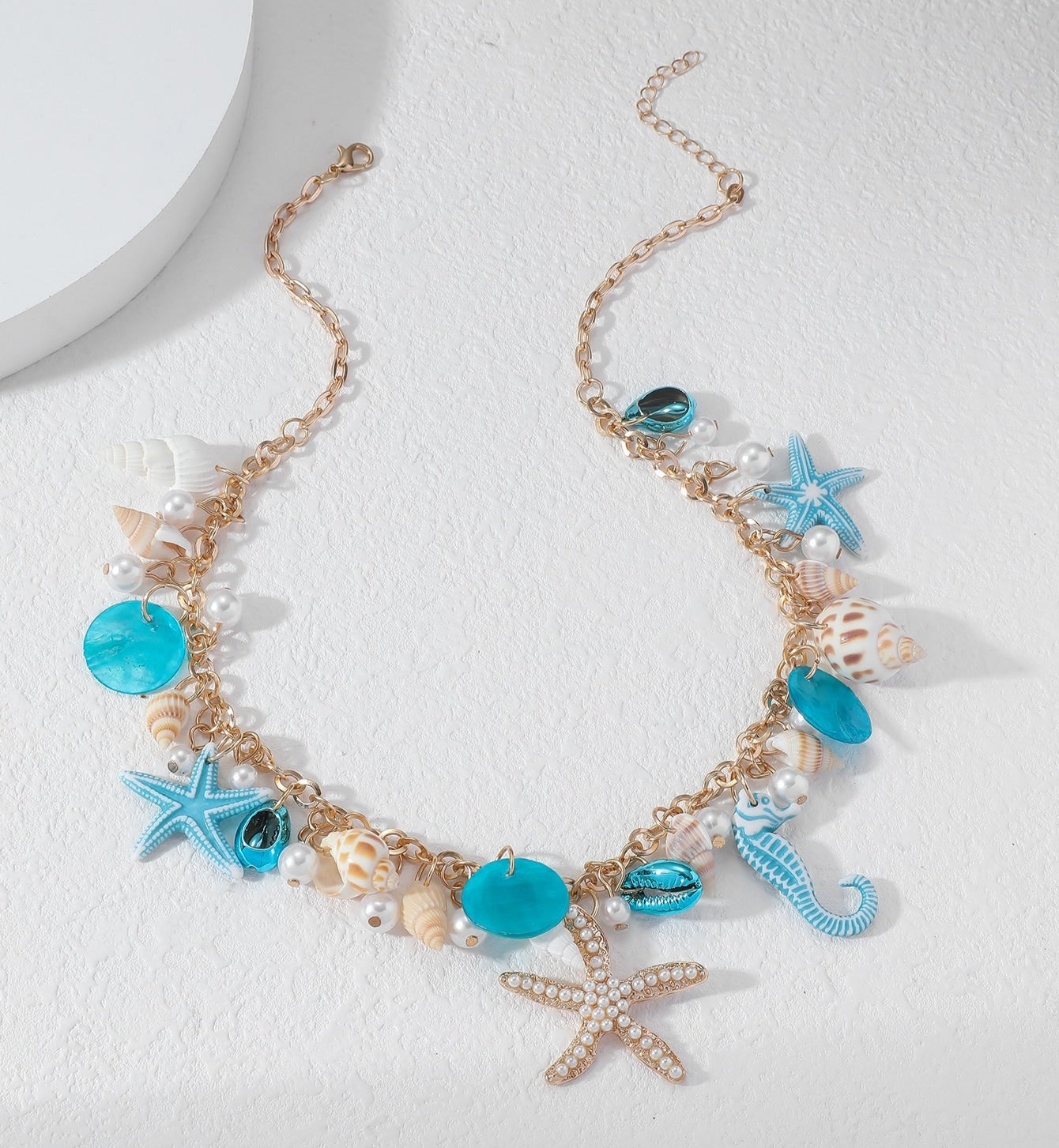 Die Tyfyy Seestern Muschel Halskette von CozyWoolCraft kombiniert goldene Kette, blaue Akzente, Muscheln, Seesterne und Perlen für einen maritimen Sommerlook.