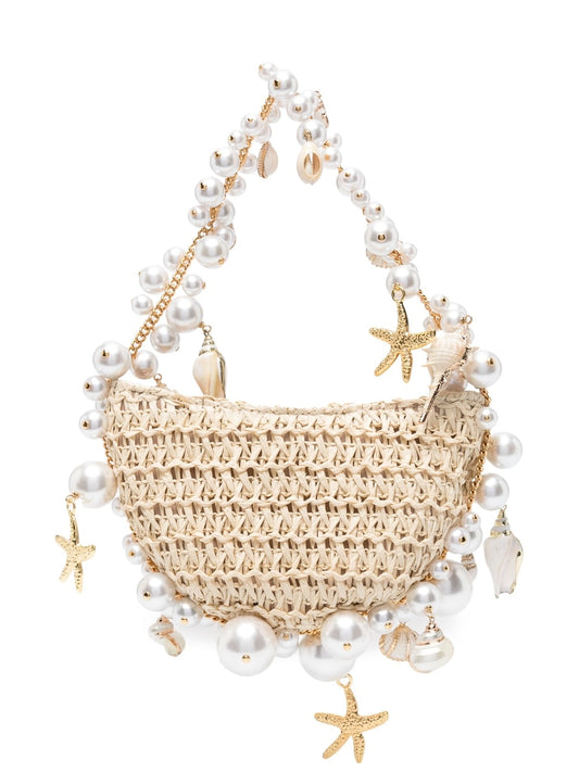 Die Ellyysa Muschel Strohhandtasche von CozyWoolCraft mit goldenen Anhängern und Perlen ist ein edles Sommer-Accessoire mit maritimem Flair.