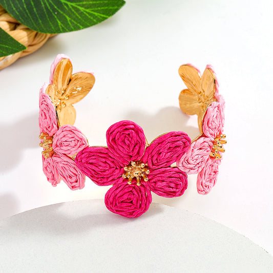 Der Jaayy Florale Armreif von CozyWoolCraft zeigt filigrane Blüten in Pink und Rosa mit goldenem Rahmen – feminines, verspieltes Statement-Accessoire.