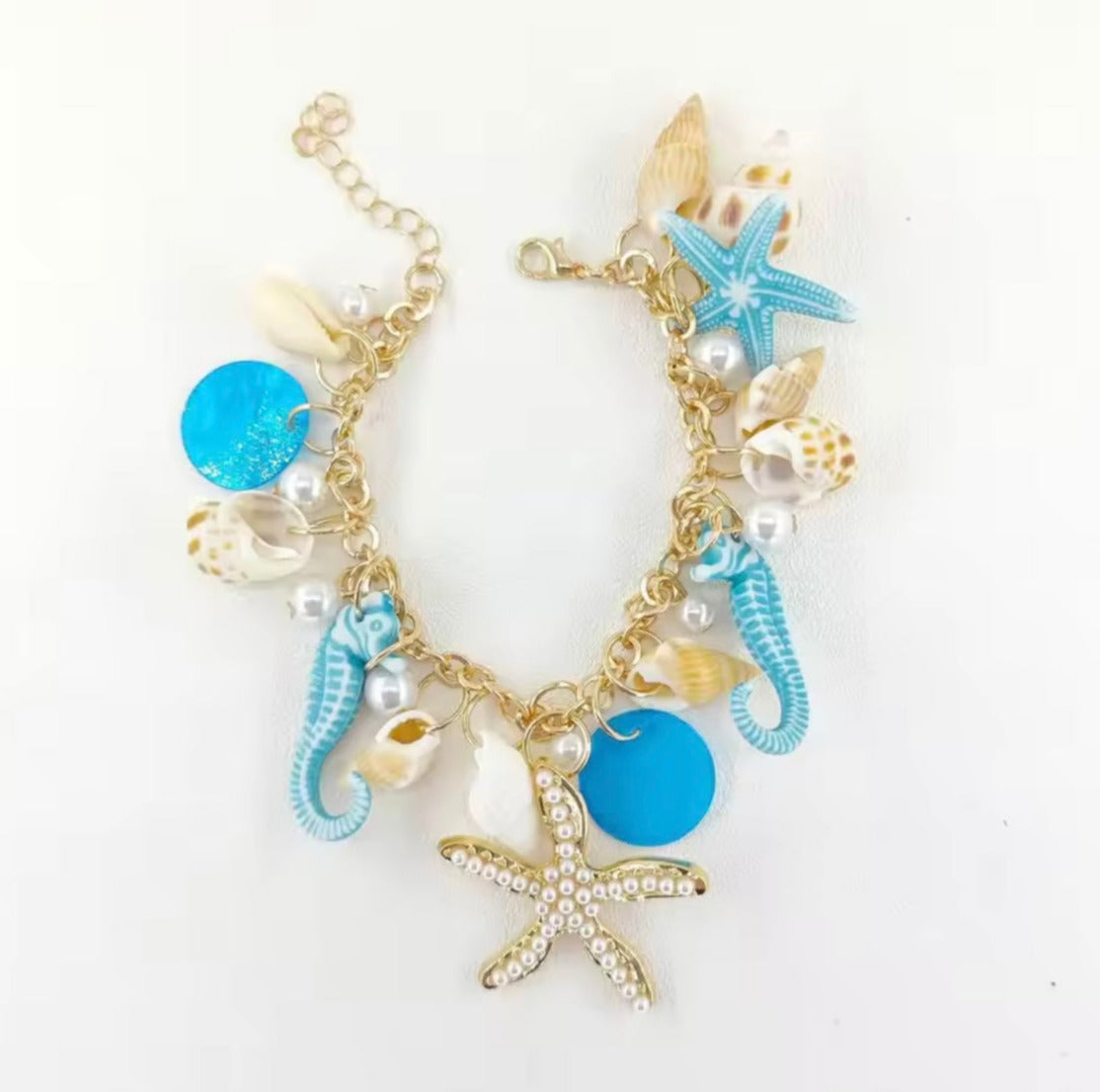 Blaues Muschelarmband mit goldener Kette, Seepferdchen- und Seestern-Anhängern, inspiriert vom Meer – CozyWoolCraft Schmuck.